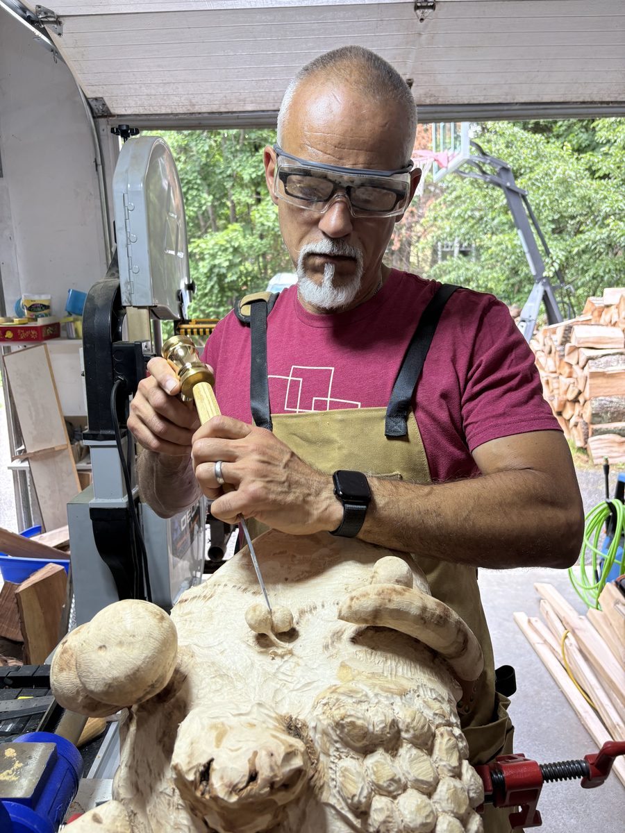 Keith in the garage workshop, chisel in hand mid-cut on a sculpture.